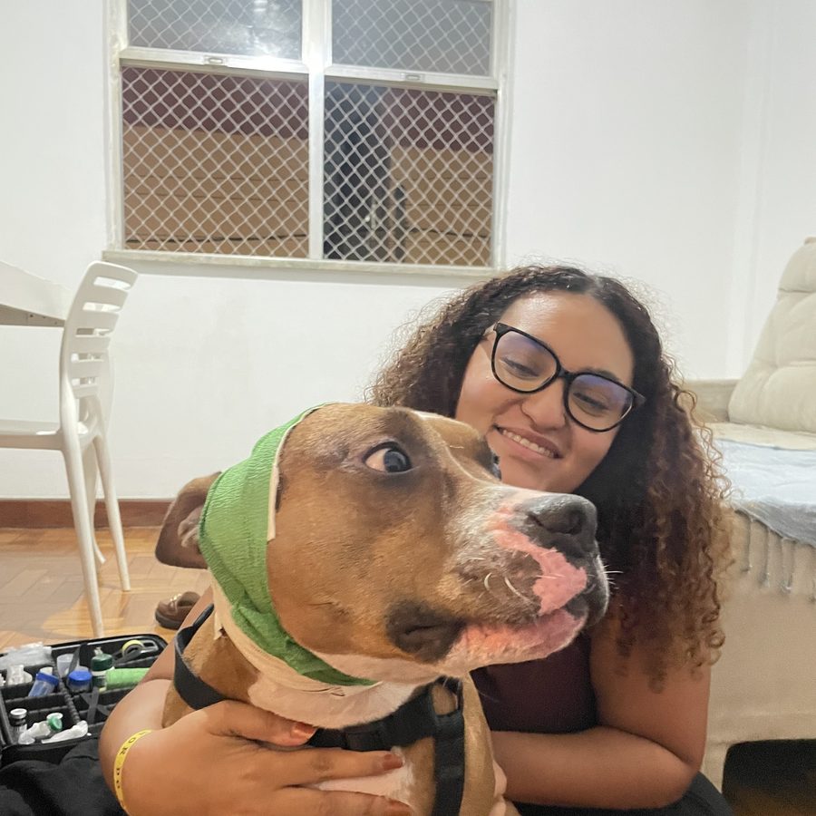 Dra. Mariana Helen atendendo o cão Eros em casa, no chão, no nível do animal